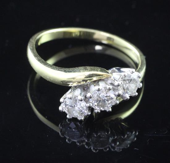 A modern 18ct gold and three stone diamond crossover ring, size O.